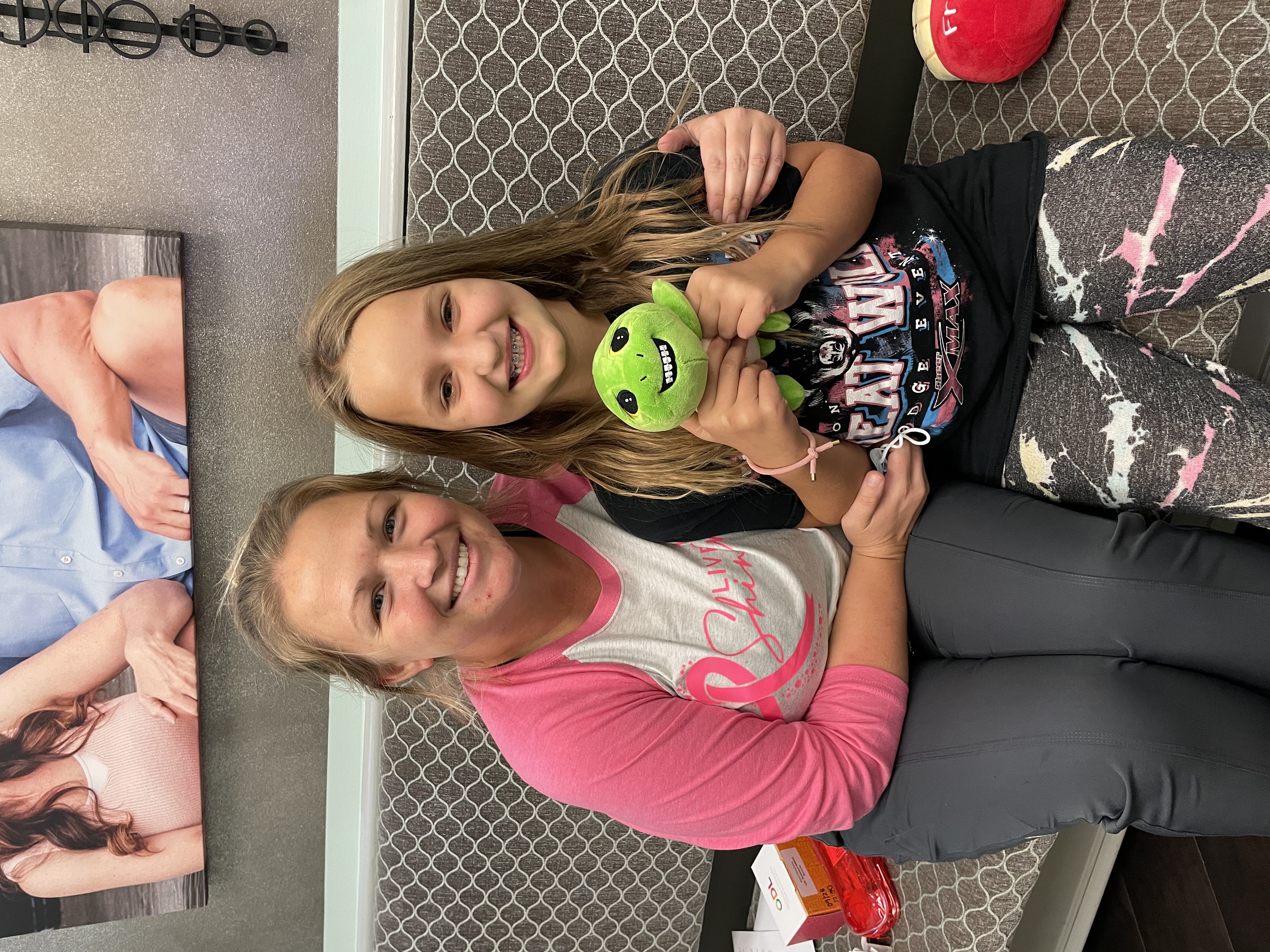 Woman and little girl smiling and holding a stuffed animal 